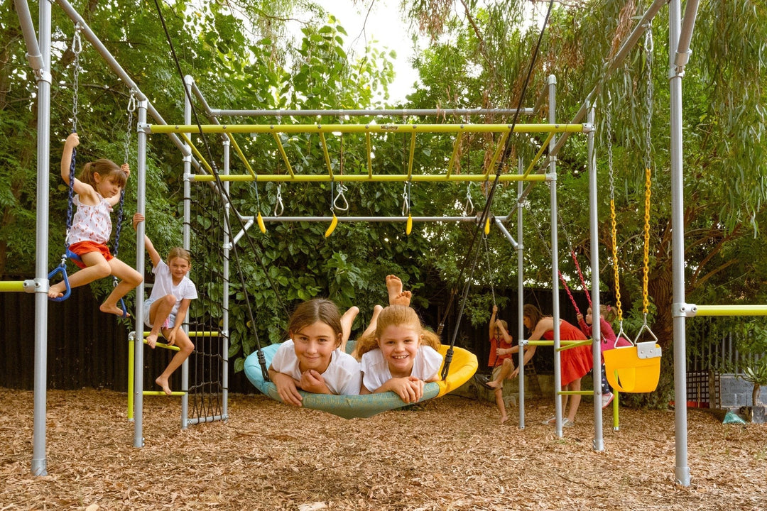 Children playing on a large Funky Monkey Bars monkey bar system with swings, climbing accessories and a nest swing in an Australian backyard.
