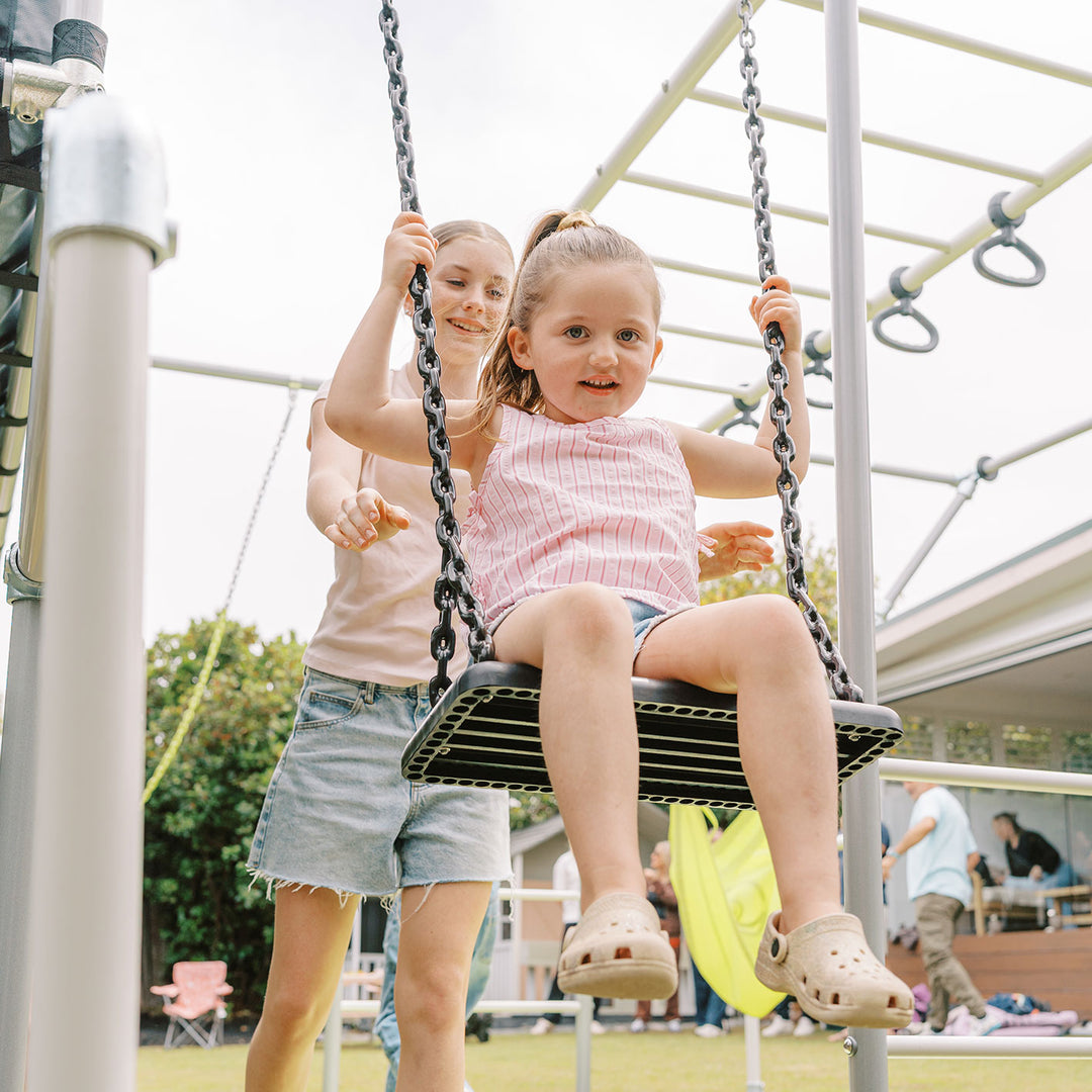Child using black rubber swing on a Funky Monkey Bars backyard monkey bar frame